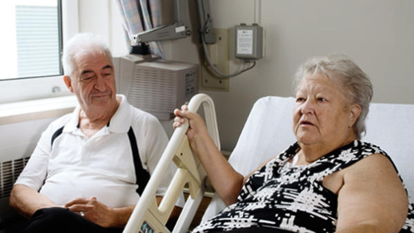 Brenda is shown in a hospital bed with a loved one by her side