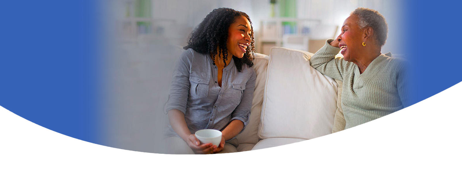 an older woman laughs on the couch with her daughter