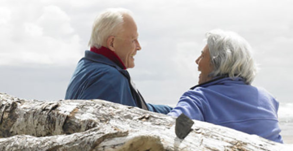 an older couple laughs at the beach